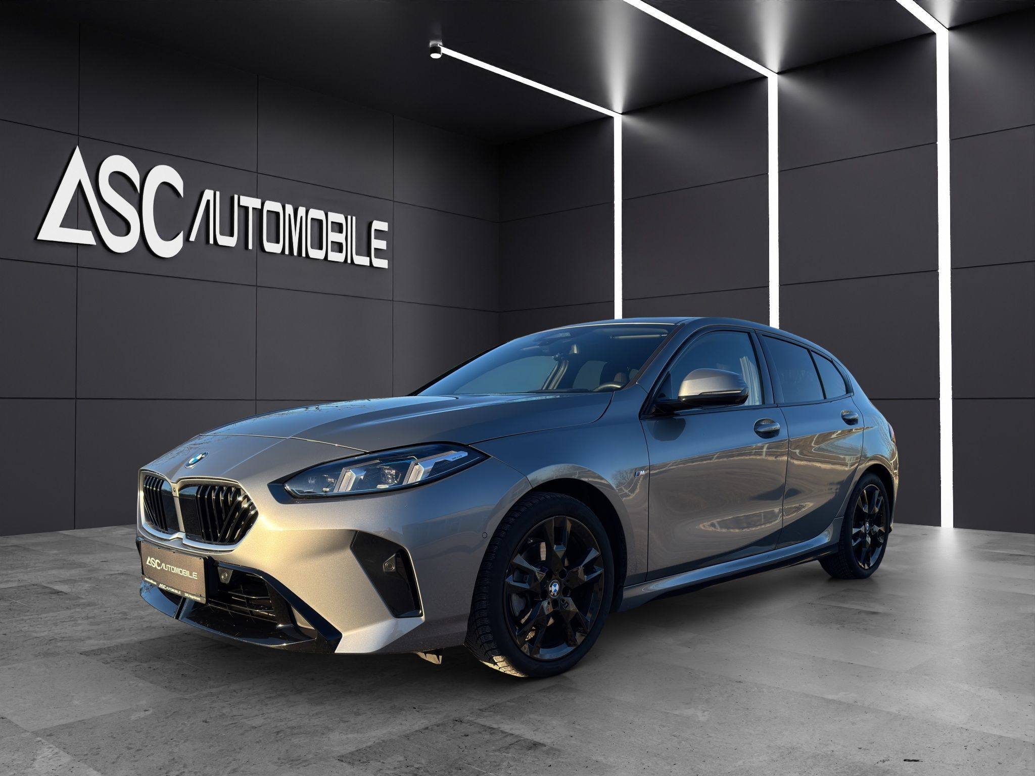 BMW 120i M Sport in Grau-Metallic, schräg von vorne links im Showroom, mit schwarzen Leichtmetallfelgen