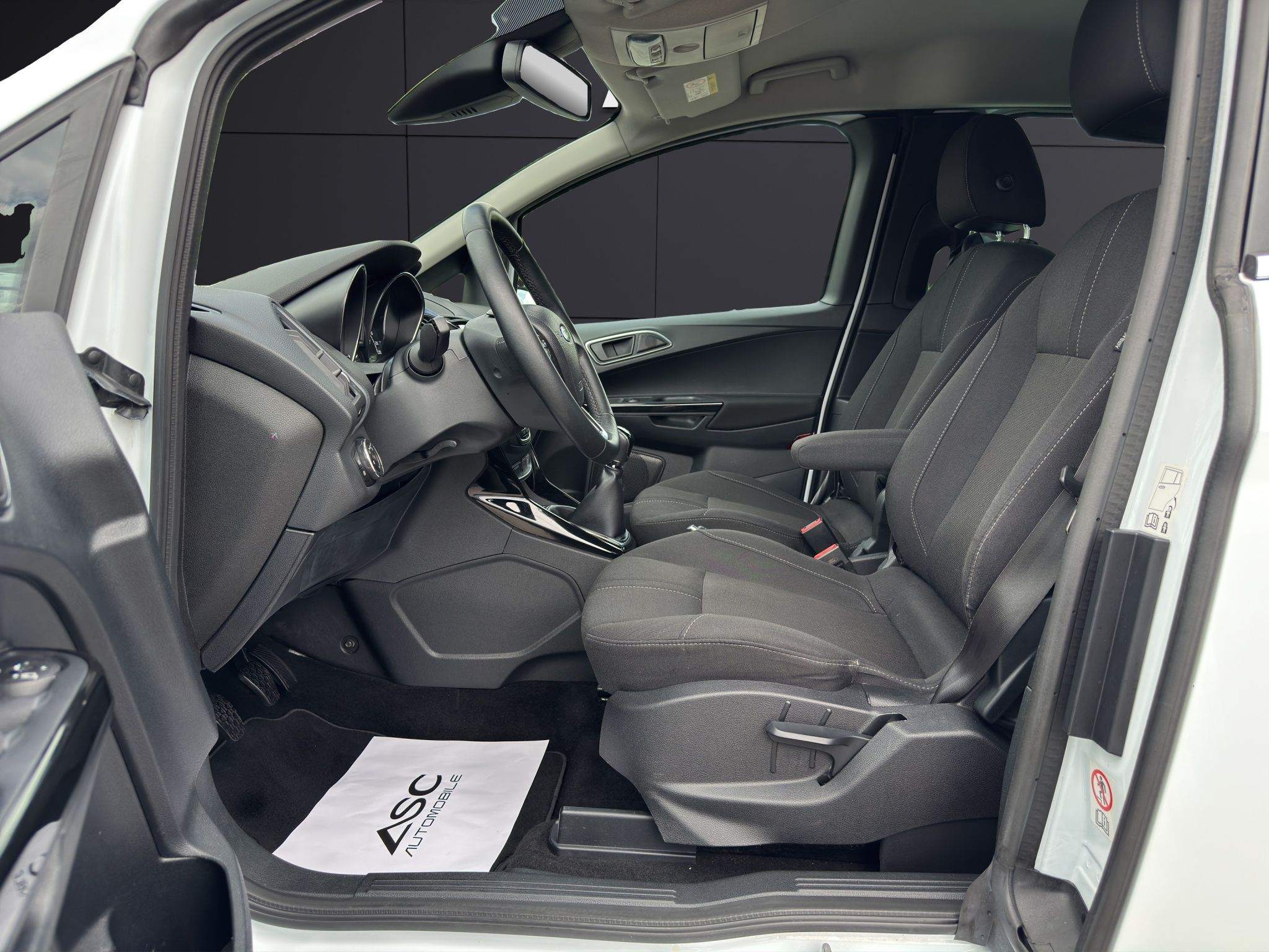Blick durch die offene Fahrertür auf die Stoffsitze und das Armaturenbrett des Ford B-MAX