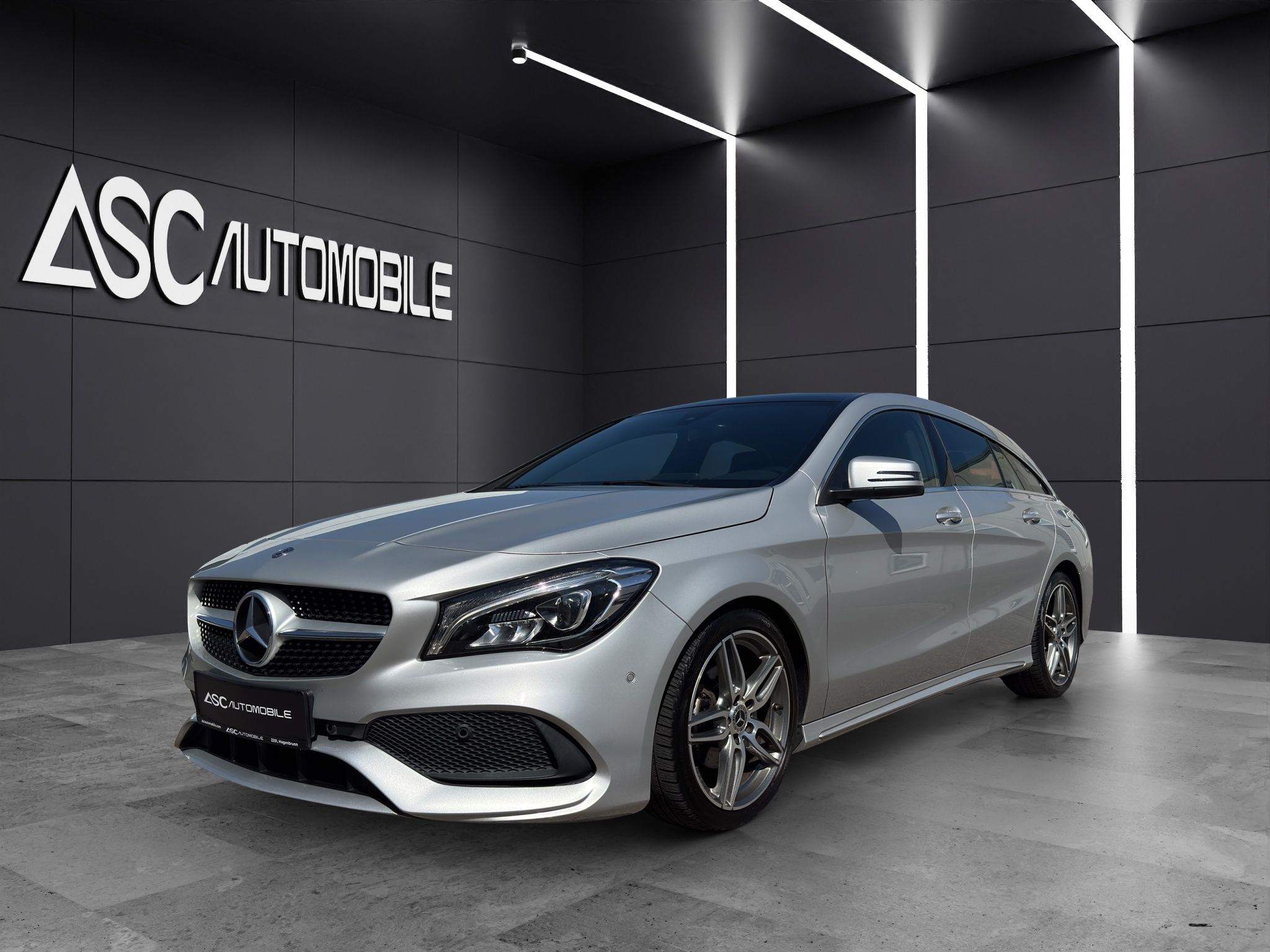 Mercedes-Benz CLA 180 Shooting Brake in Silber, schräg von vorne links im Showroom, mit AMG Line-Stoßfänger