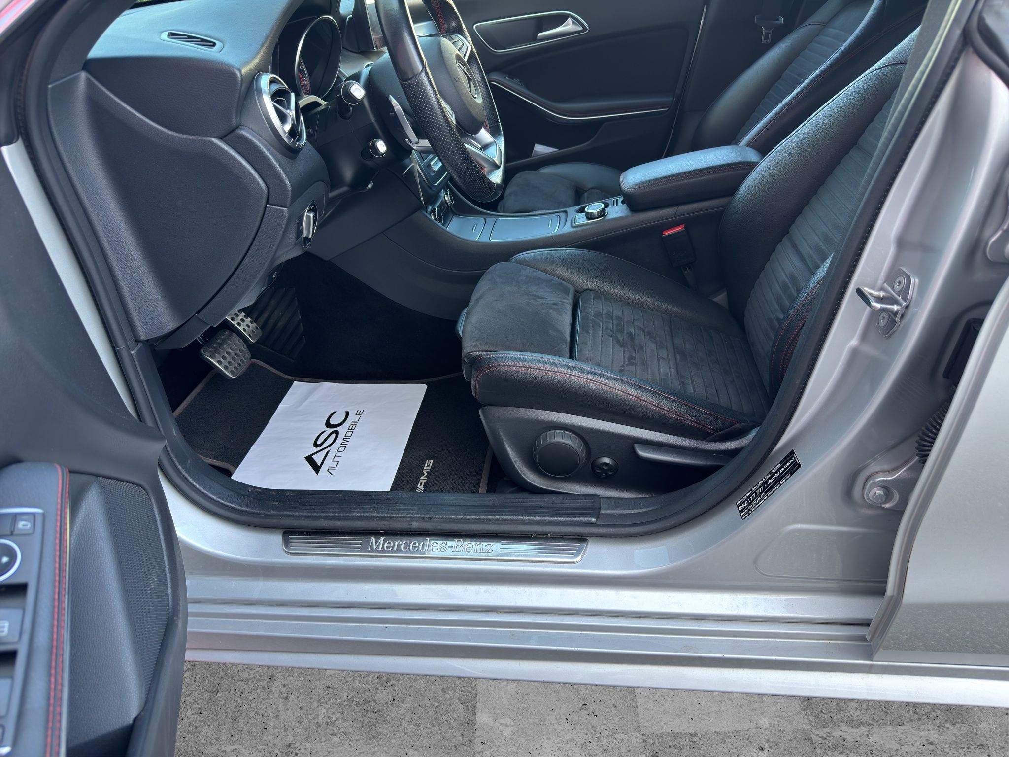 Blick durch die offene Fahrertür auf die Sportsitze des Mercedes CLA 180 in Schwarz mit roten Ziernähten