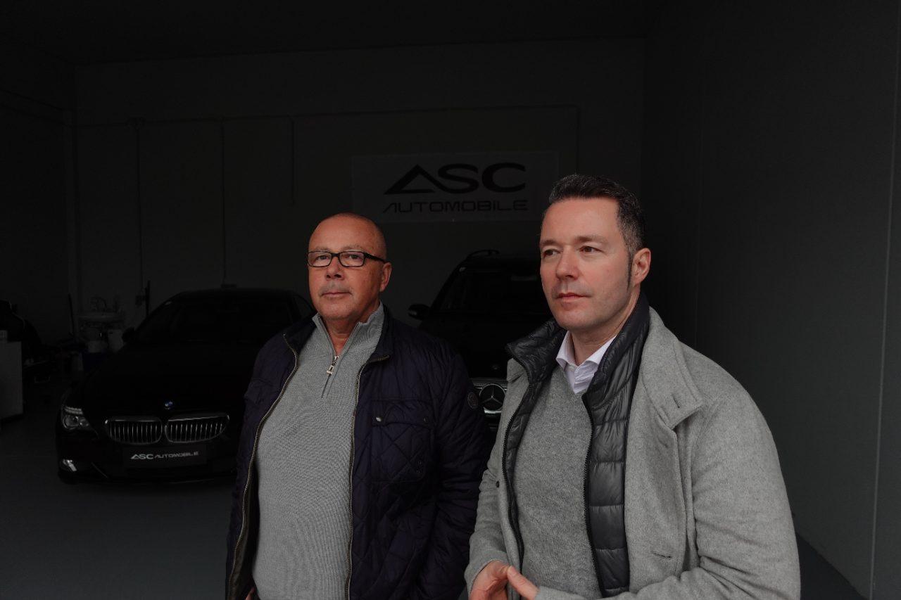 Amir und Senad Cizmic im Showroom von ASC Automobile, dahinter ein schwarzer BMW und ein schwarzer Mercedes