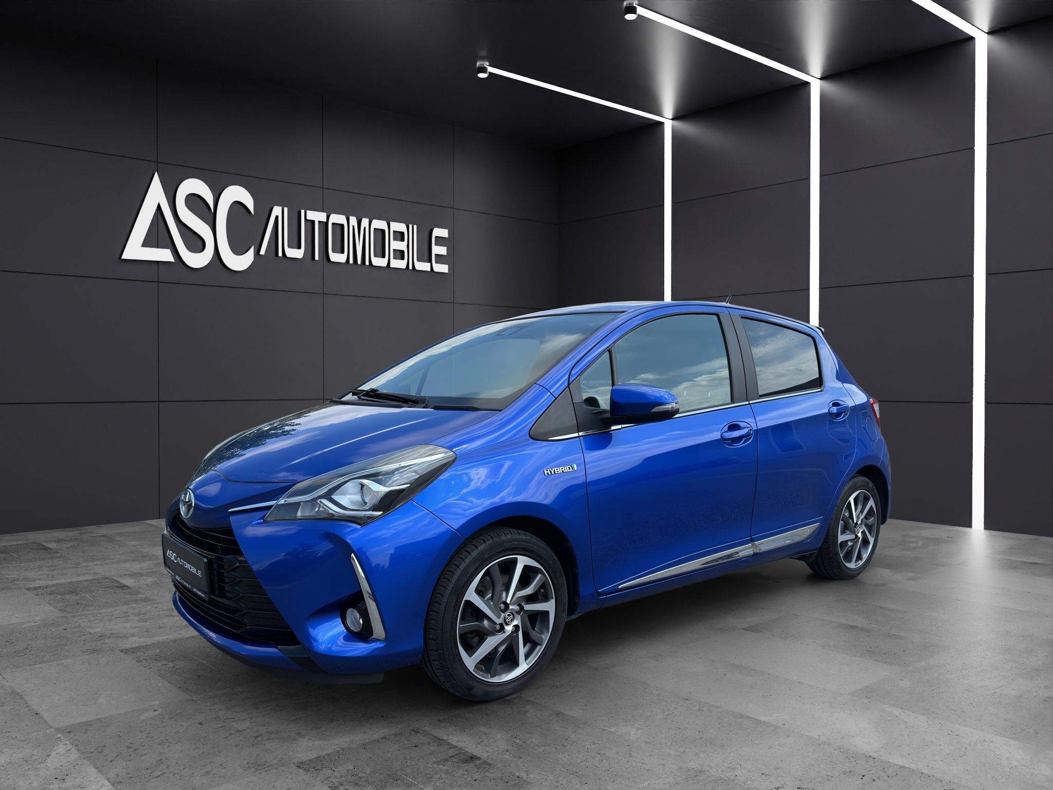 Toyota Yaris Hybrid in Blau, schräg von vorne links im Showroom von ASC Automobile