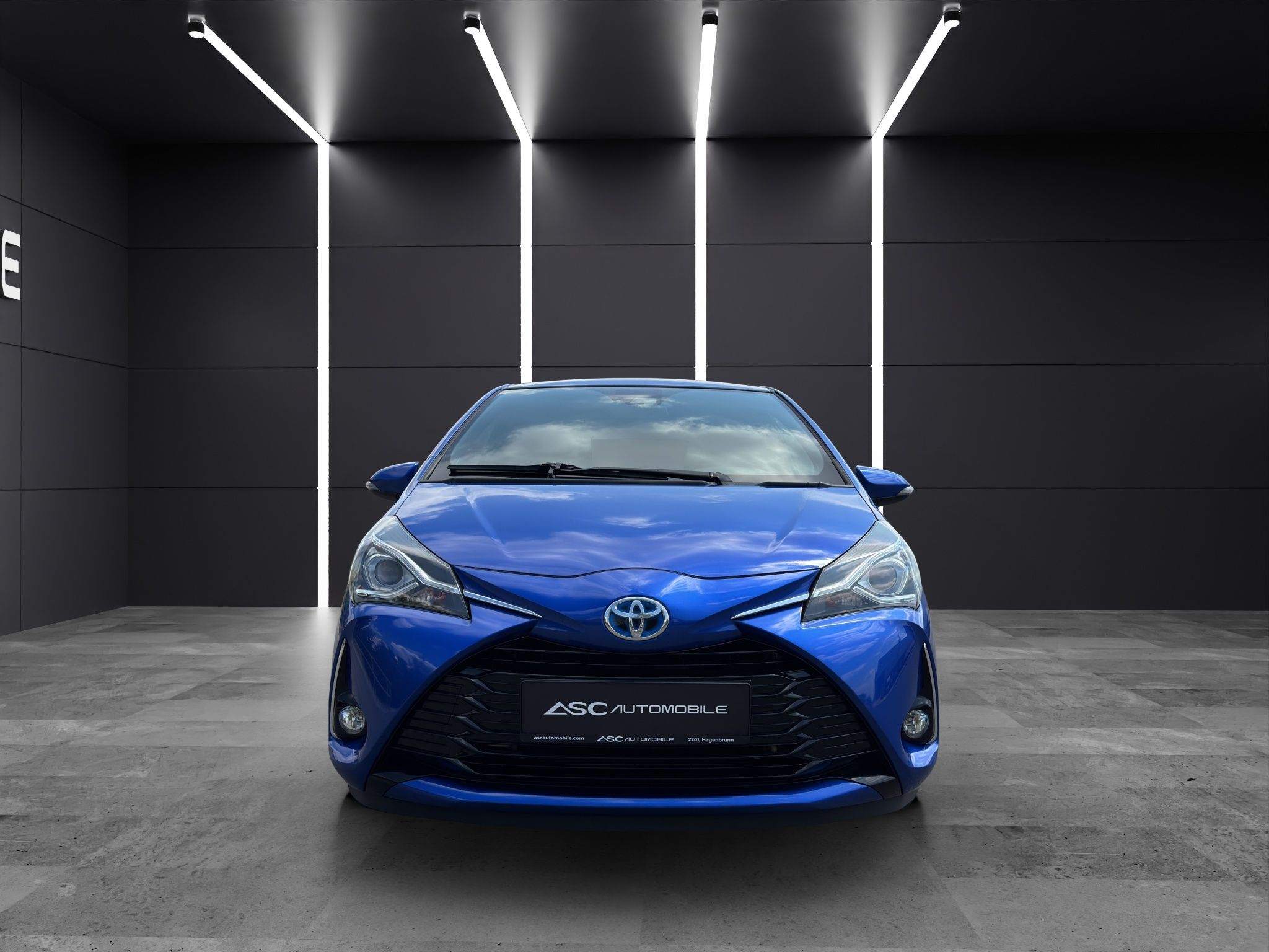 Toyota Yaris Hybrid in Blau von vorne im Showroom von ASC Automobile